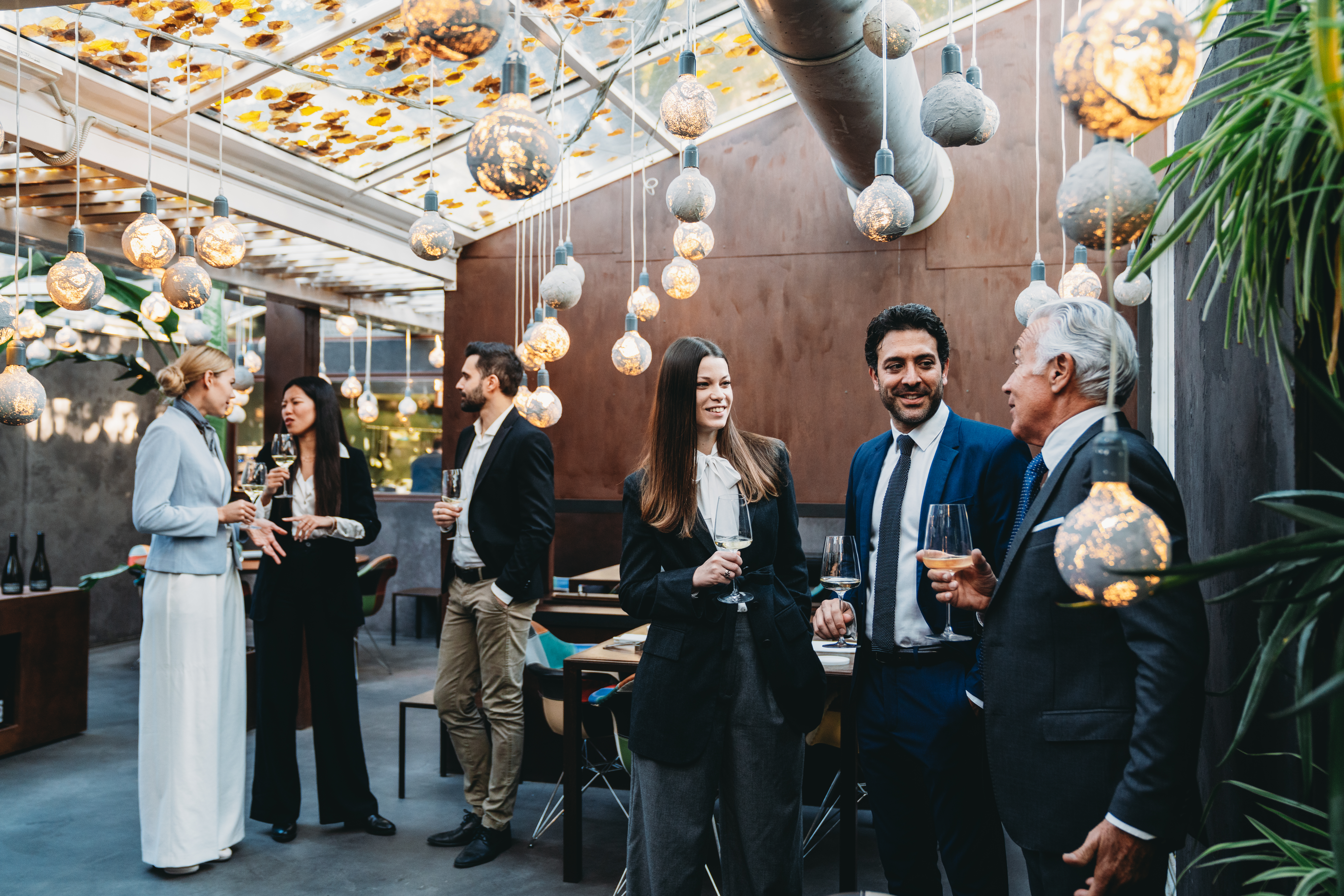 Business people are talking together during a teambuilding event in a luxury restaurant. They are drinking wine, waiting for the dinner.